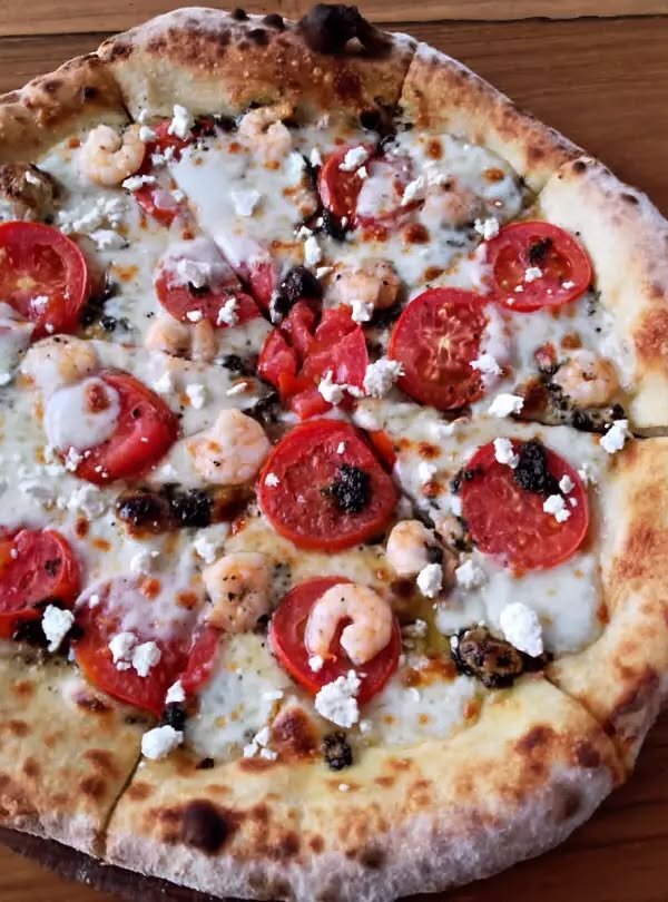 Wood-fired pizza topped with fresh ingredients at Fellas Pizzeria in Labuan Bajo, Flores, Indonesia