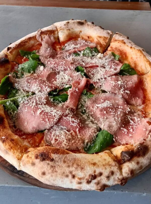 Wood-fired pizza topped with fresh ingredients at Fellas Pizzeria in Labuan Bajo, Flores, Indonesia