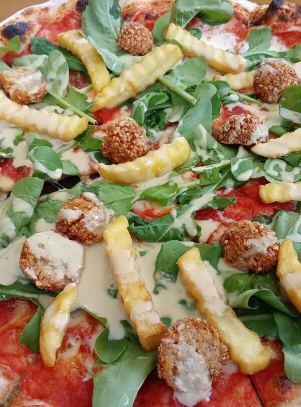 Wood-fired pizza topped with fresh ingredients at Fellas Pizzeria in Labuan Bajo, Flores, Indonesia