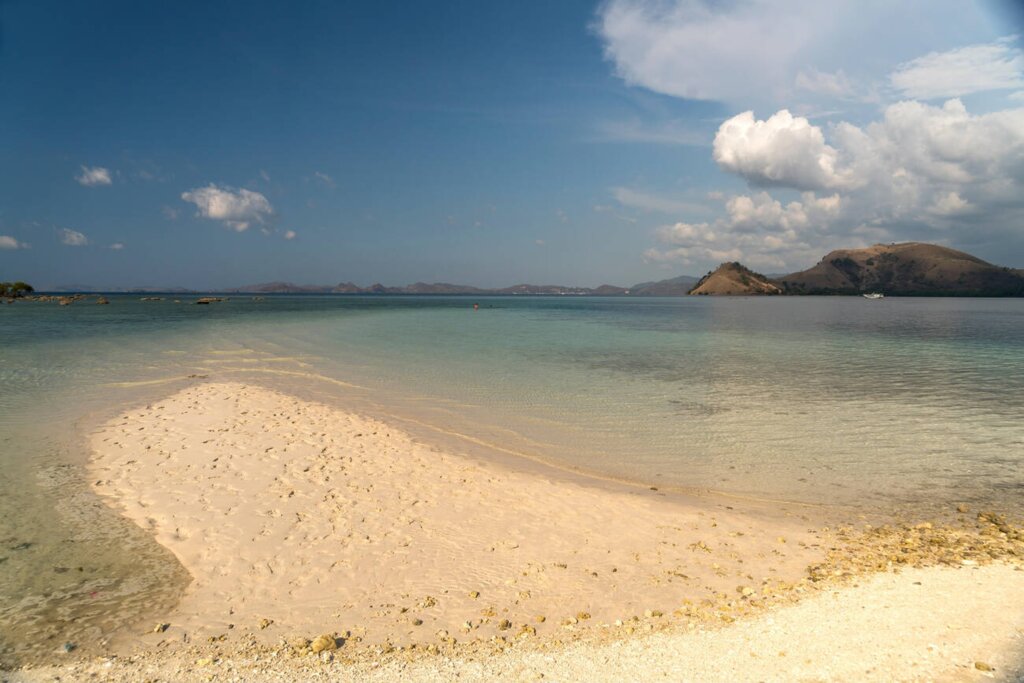 Aerial view of Kelor Island with its lush green hill and white sandy beach in Labuan Bajo