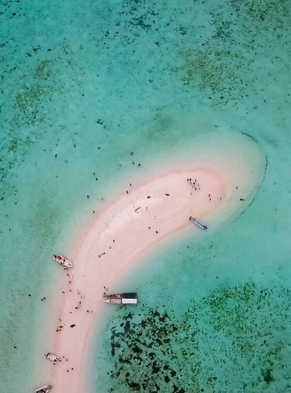 Aerial view of Taka Makassar’s crescent-shaped sandbar surrounded by turquoise waters