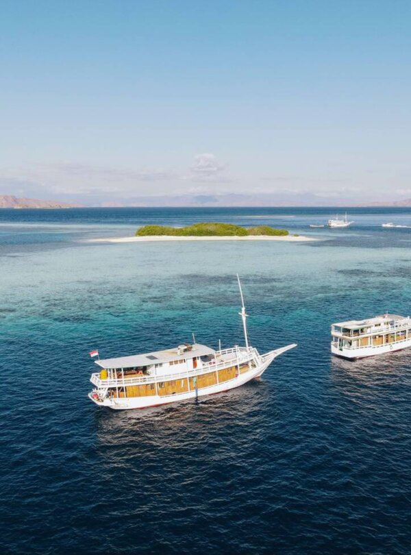 Aerial view of Taka Makassar’s crescent-shaped sandbar surrounded by turquoise waters