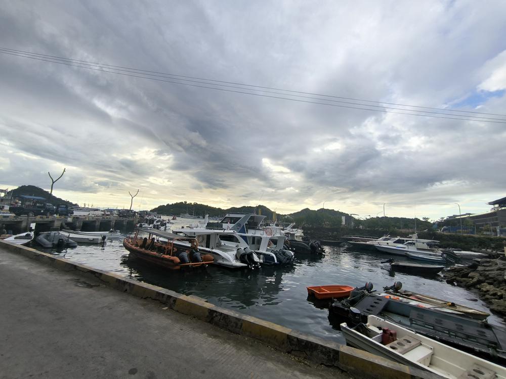 Scenic view of boats and yachts docked at Marina Waterfront Labuan Bajo with hills in the background