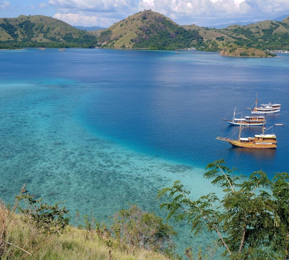 Kelor Island – Hilltop Views and White Sand Beach in Labuan Bajo Aerial view of Kelor Island with its lush green hill and white sandy beach in Labuan Bajo