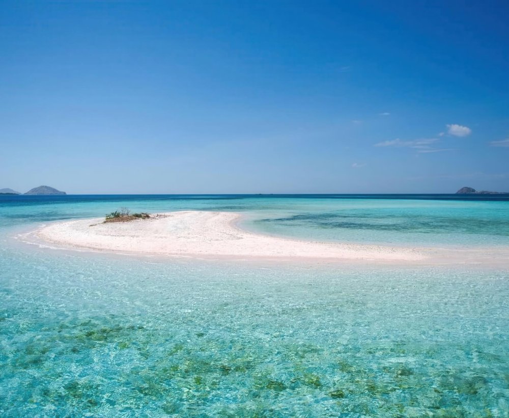 Taka Makassar – Crescent Sandbar in the Flores Sea Aerial view of Taka Makassar’s crescent-shaped sandbar surrounded by turquoise waters