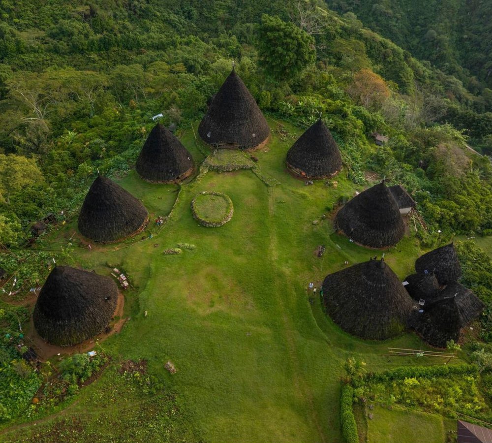Wae Rebo Village – The Hidden Traditional Village in the Clouds Traditional conical houses of Wae Rebo Village surrounded by lush green mountains in Flores, Indonesia