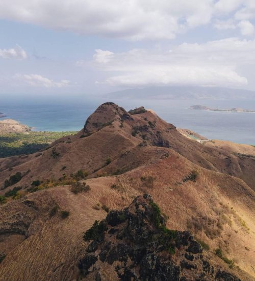 Golo Mori – The Scenic Coastal Gem of Flores Panoramic view of Golo Mori’s coastline with turquoise waters and rolling green hills in Flores, Indonesia